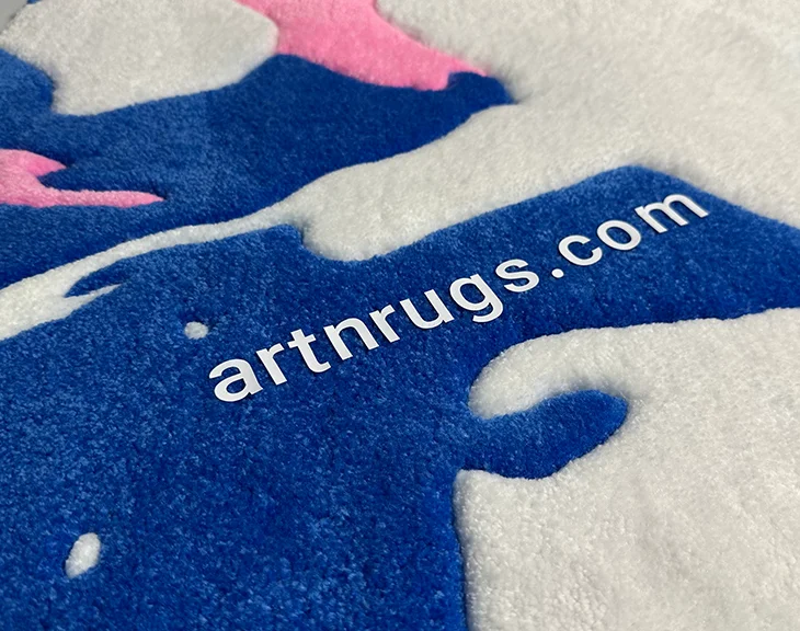 detal marki: logo artnrugs.com na niebiesko-biało-różowym abstrakcyjnym ręcznie tuftowanym dywanie Ksenii Derr