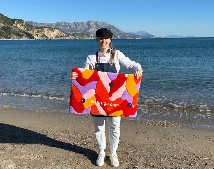 Personne exposant le Tapis Parquet Rouge et Orange devant la mer et les montagnes